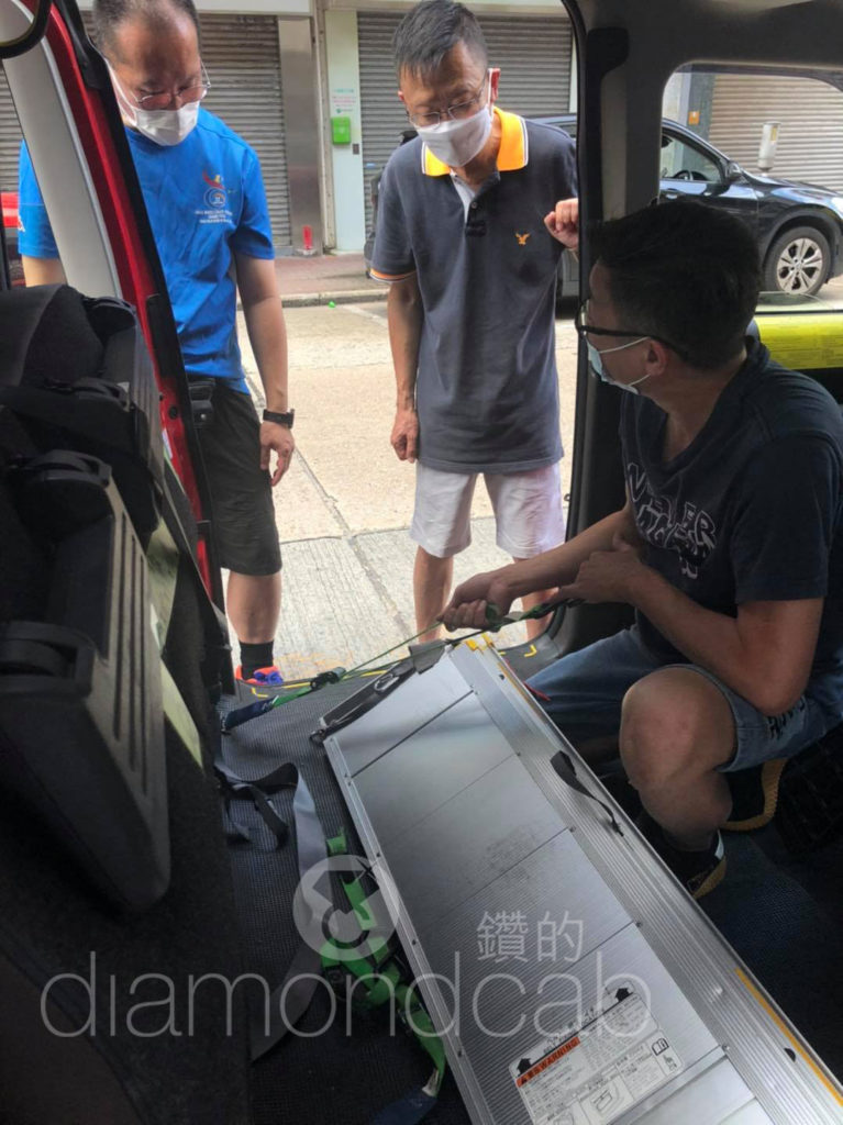 Three men discussing how to lower a ramp for a DiamondCab taxi. 三名男子討論如何降下「鑽的」的士的斜板。